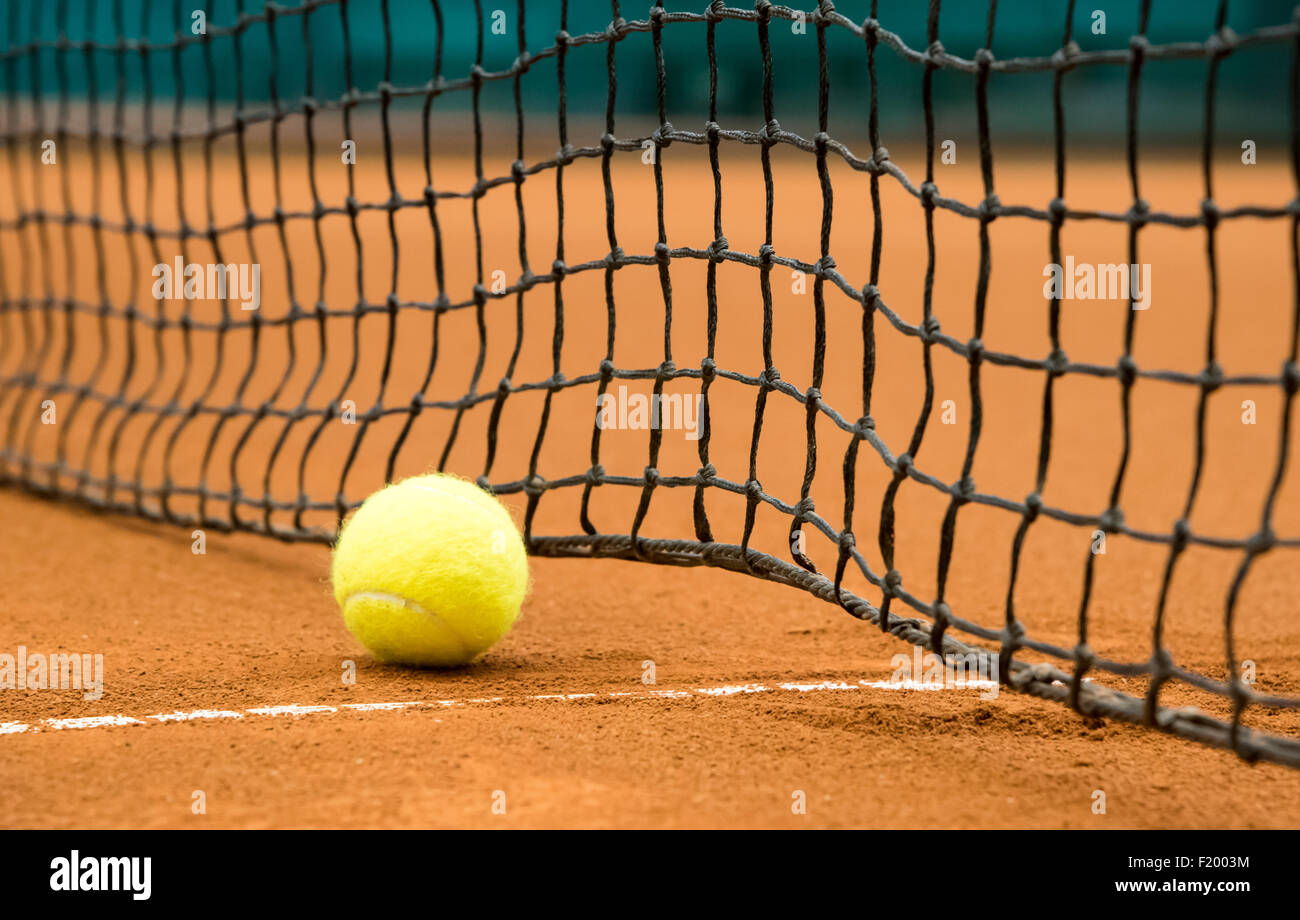 yellow tennis ball on a red clay court Stock Photo