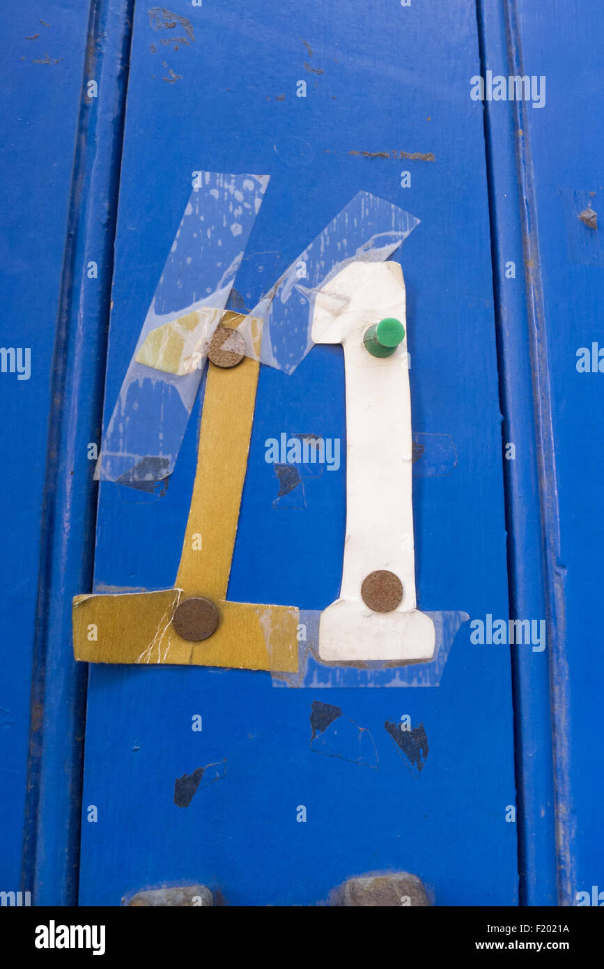 Spitalfields, London. Pinned and taped cardboard numbers, number eleven 11, on a blue painted panelled door. Stock Photo