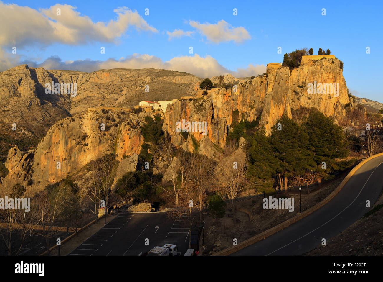 Setting Sun reflecting on Guadalest Castle rocks and Mountains beyond Stock Photo