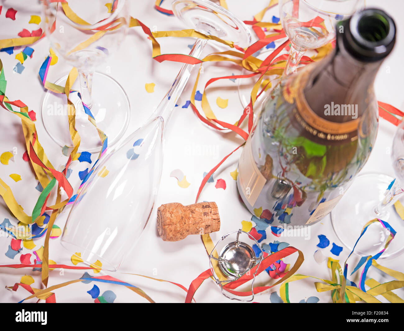 Offene Sektflasche und leere Gläser mit Papierschlangen und Konfetti Stock Photo