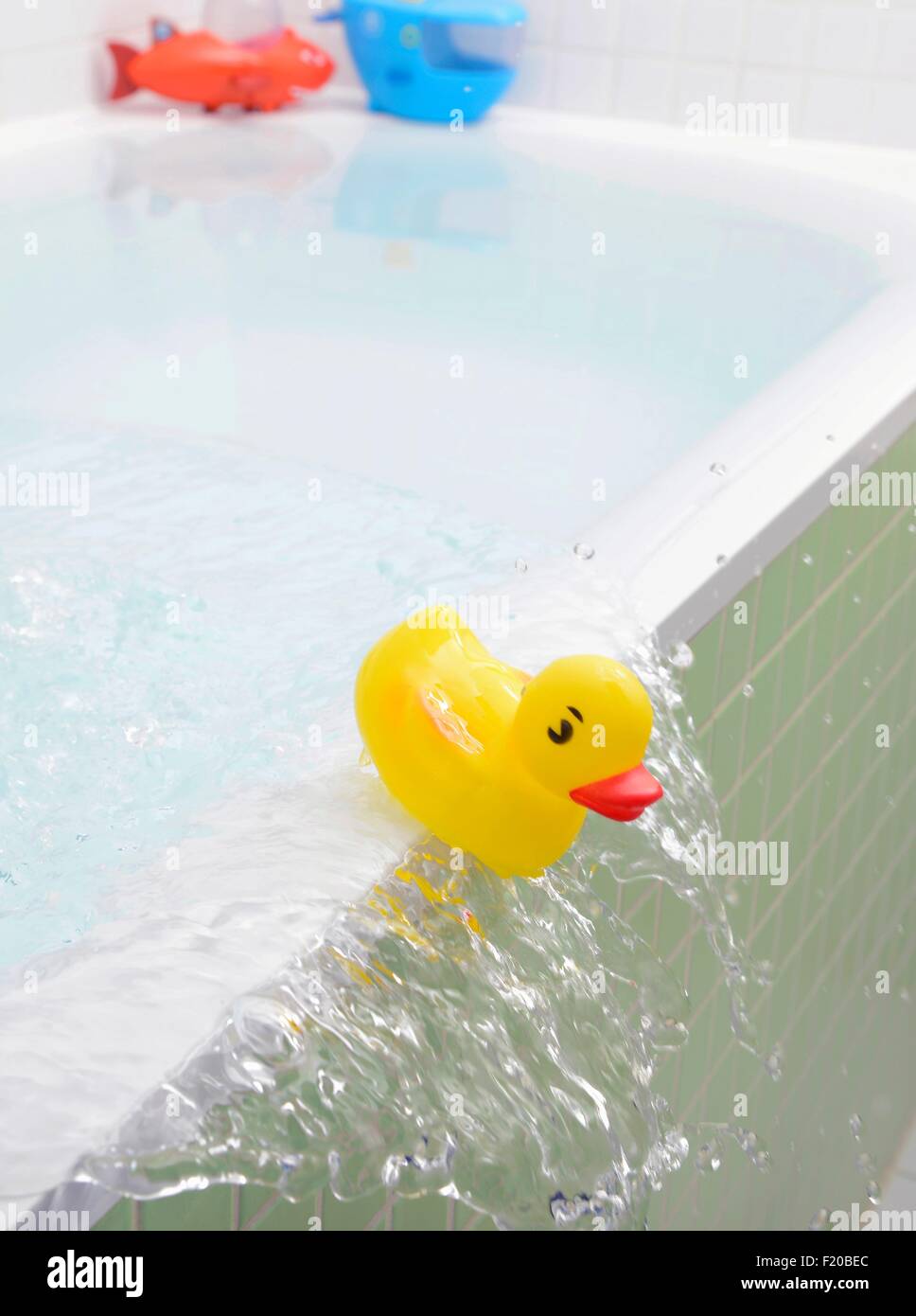 Rubber duck falling out of bath overflowing with water Stock Photo