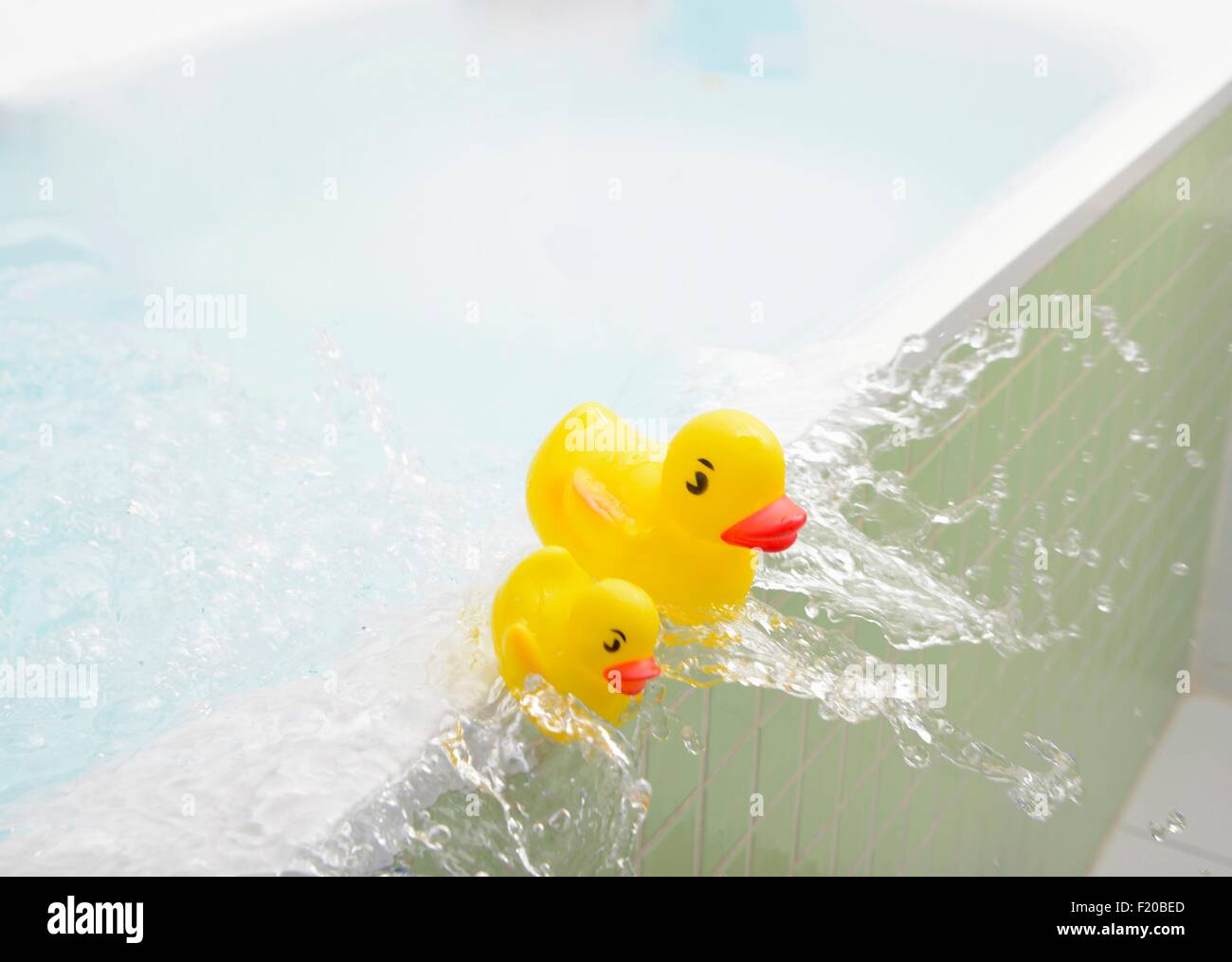 Rubber ducks falling out of bath overflowing with water Stock Photo