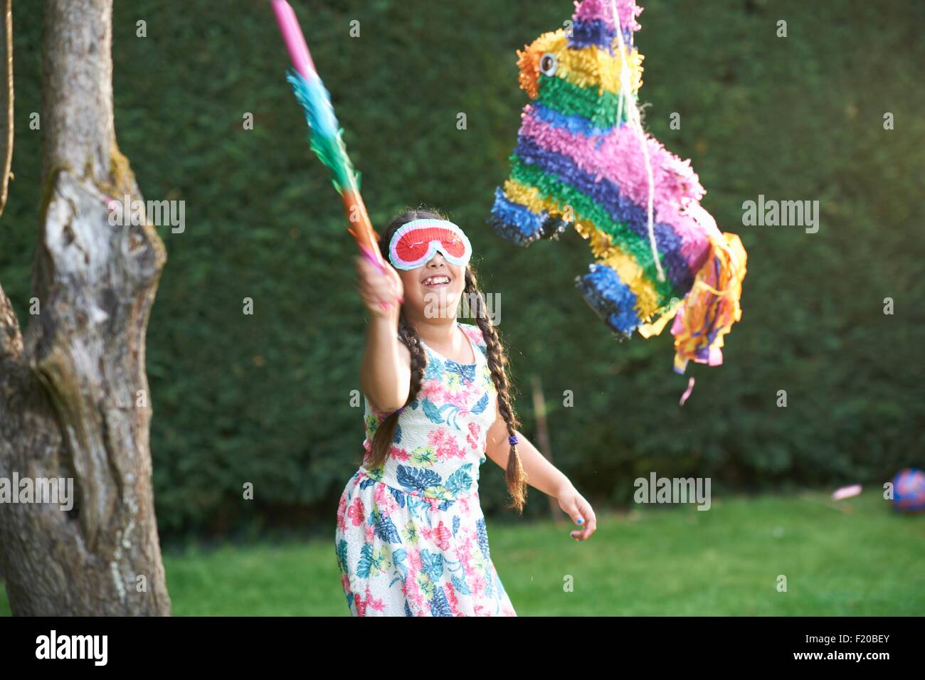 Girl playing pinata in garden Stock Photo