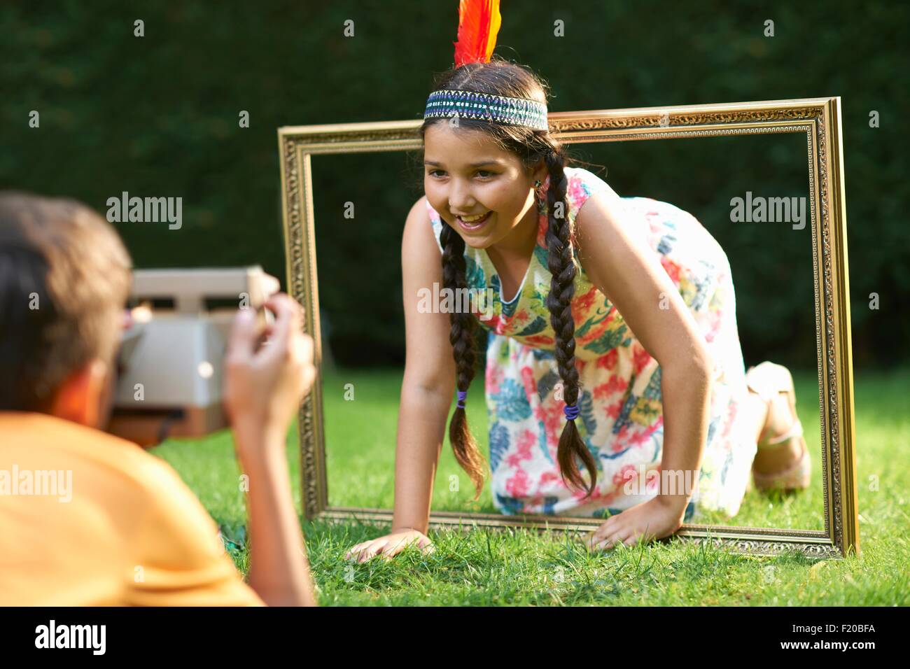 Girl kneeling, looking through picture frame, having photograph taken Stock Photo