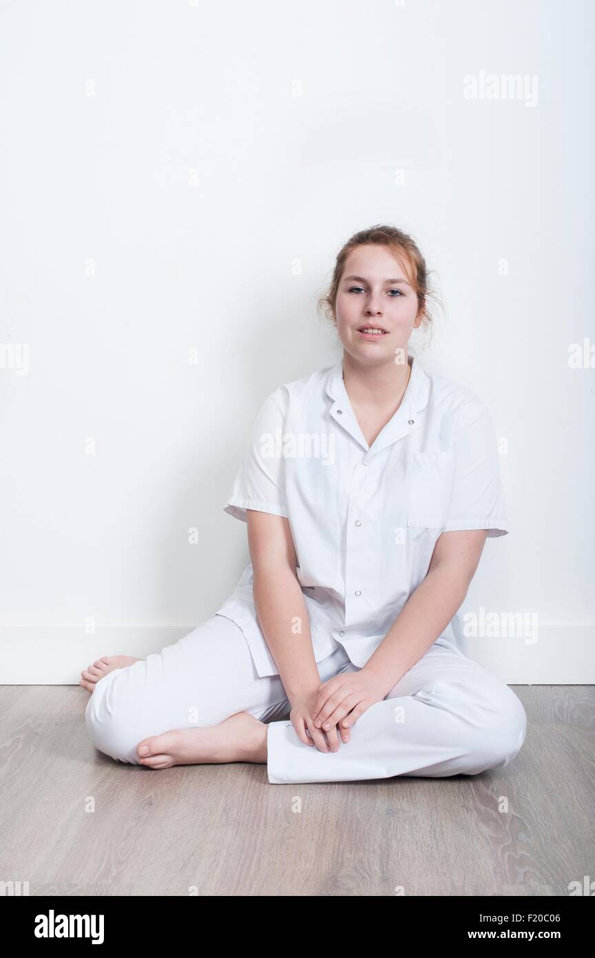 Portrait of young nurse sitting on floor Stock Photo