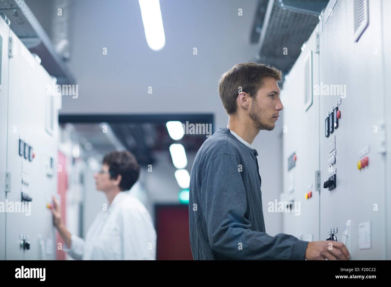 Scientist and technician monitoring control panel in technical room