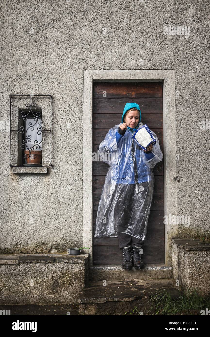 Young woman wearing rain mac standing in doorway, Lake Como, Italy Stock Photo