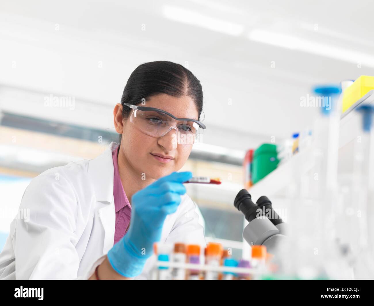 Young woman scientist viewing blood tube during clinical testing of medical samples in a laboratory Stock Photo