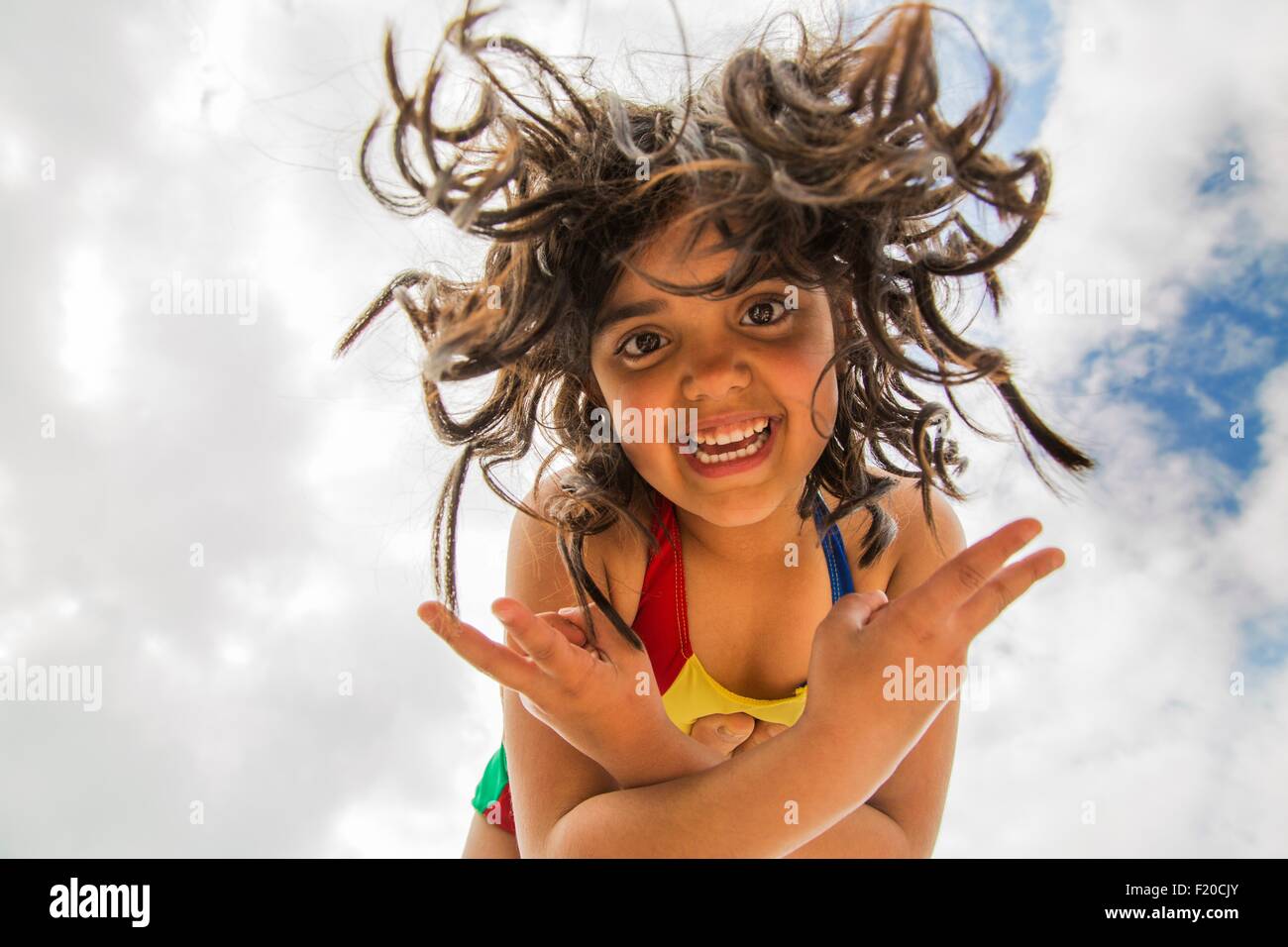 Low angle portrait of girl with long curly hair balancing on top of someones foot Stock Photo