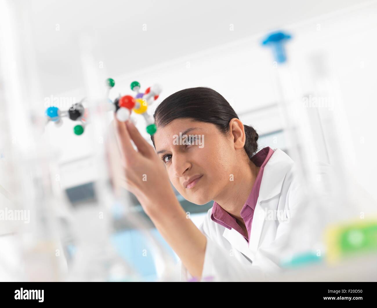 Female scientist in laboratory, viewing molecular model of a chemical formula Stock Photo