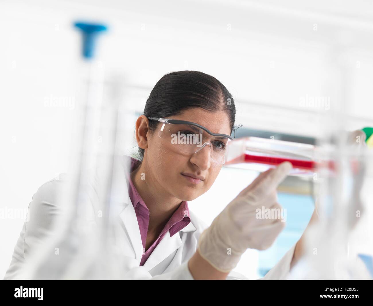 Female biologist in laboratory, holding a flask containing stem cells Stock Photo