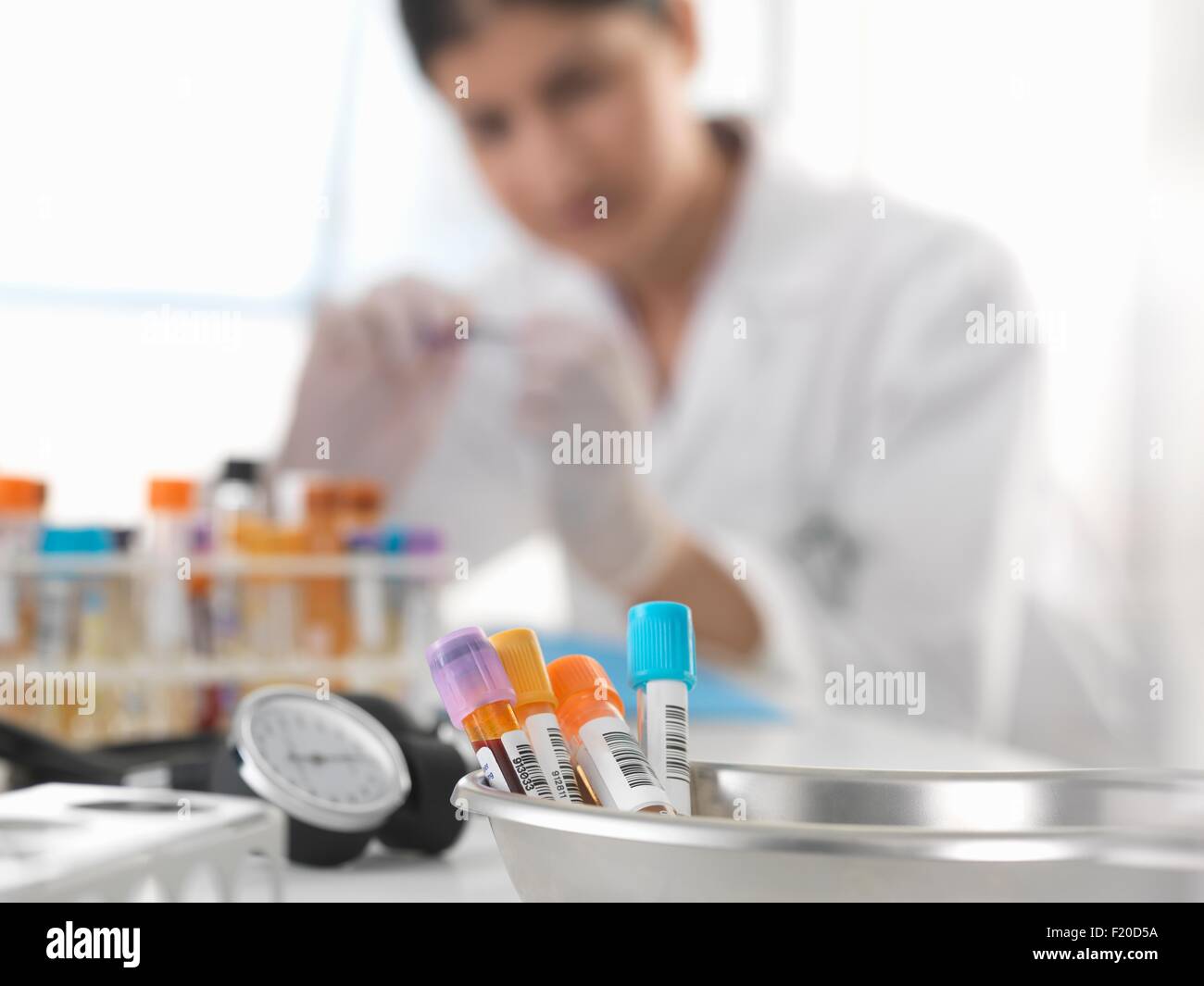 Female doctor inspecting blood sample at desk Stock Photo