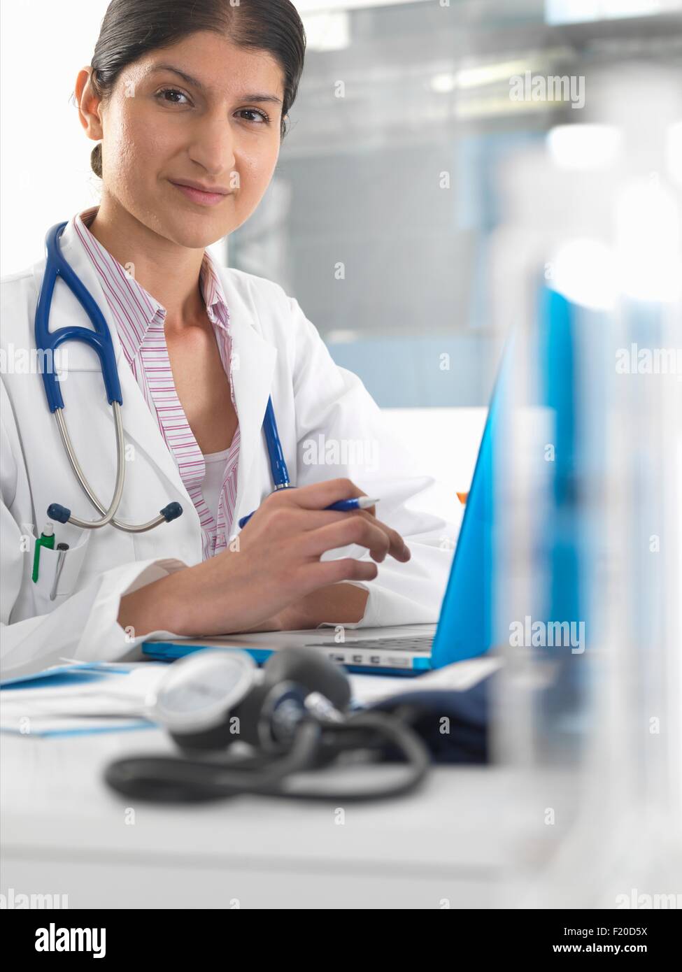 Portrait of female doctor at desk working on laptop Stock Photo
