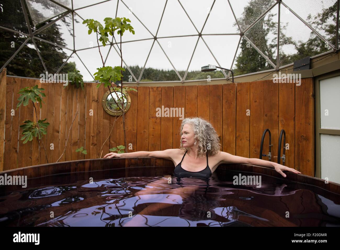 Mature woman relaxing in hot tub at eco retreat Stock Photo