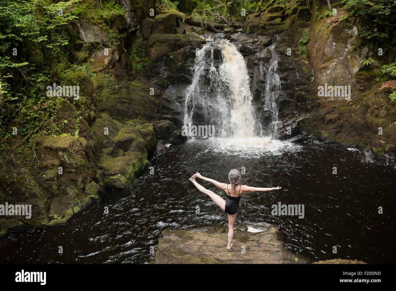 Rear view of mature woman practicing yoga in front of waterfall Stock ...