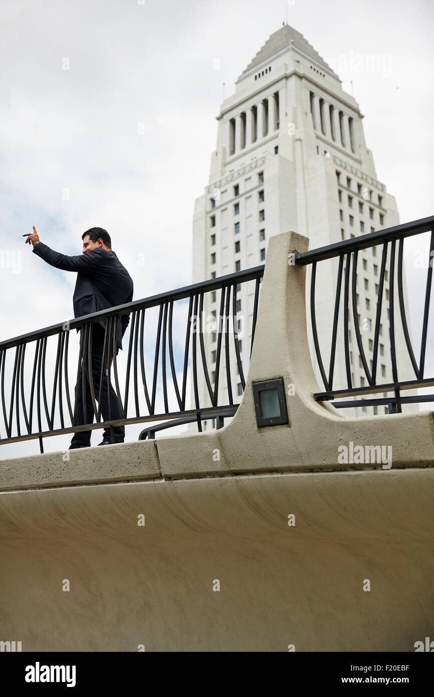 Side view of business man standing on walkway, hand raised, Los Angeles City Hall, California, USA Stock Photo