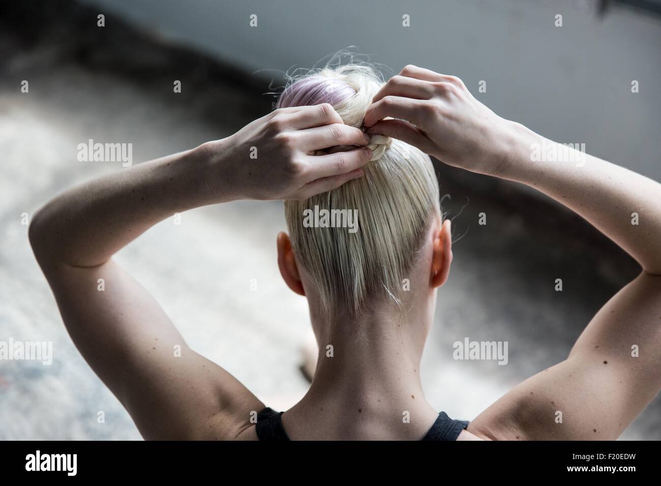 Woman tying up hair in studio Stock Photo