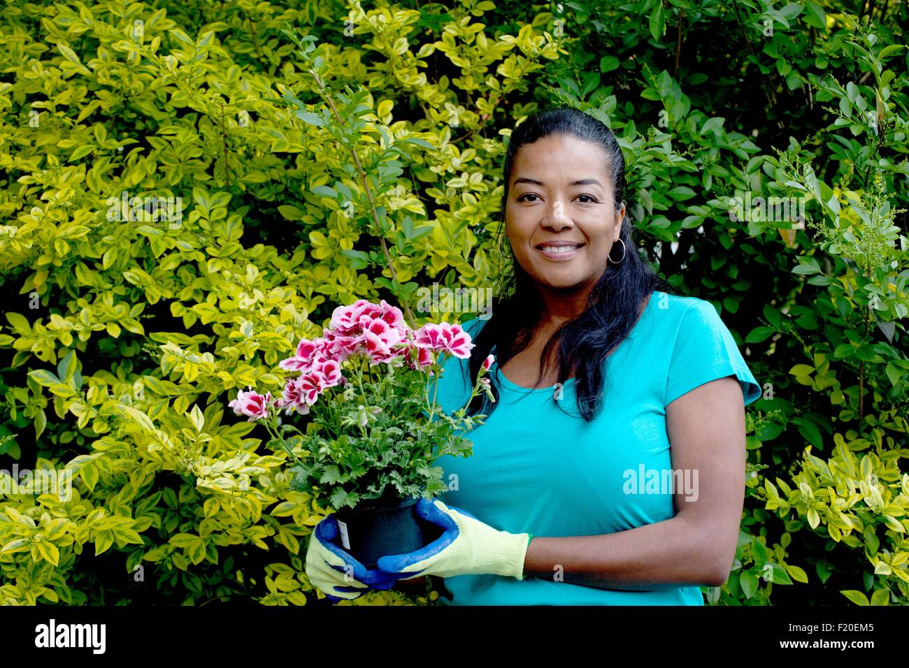 Portrait of mature woman with flowering pot plant in garden Stock Photo ...