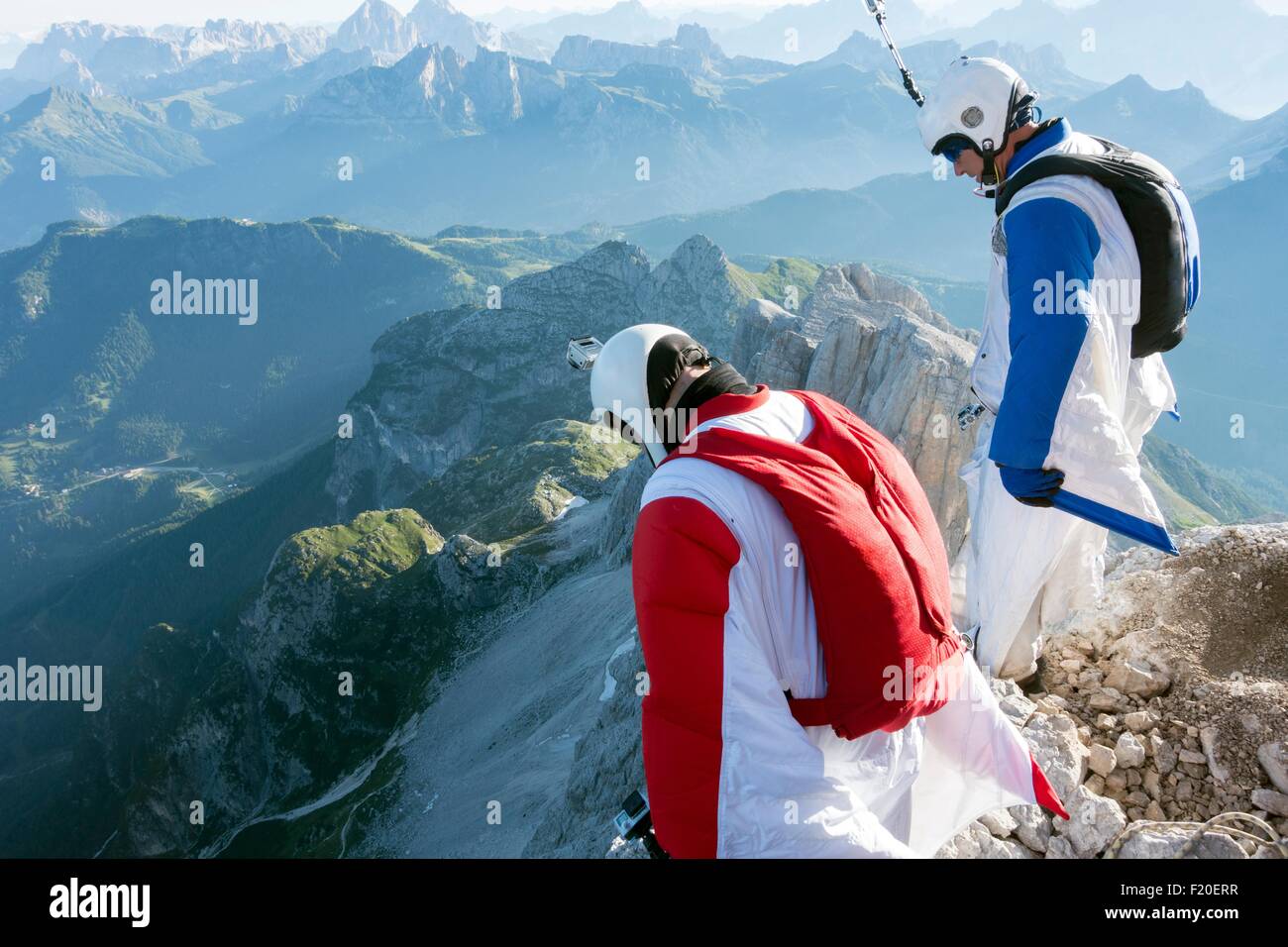 Two male BASE jumpers standing on edge of mountain looking down, Dolomites, Italy Stock Photo