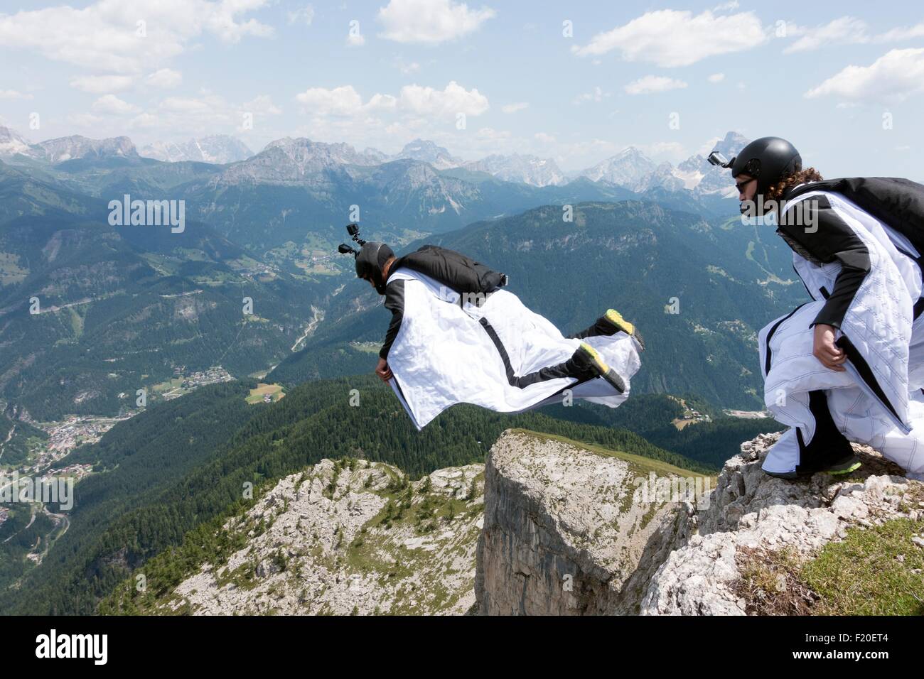 Two male BASE jumpers exiting from mountain top, Dolomites, Italy Stock Photo