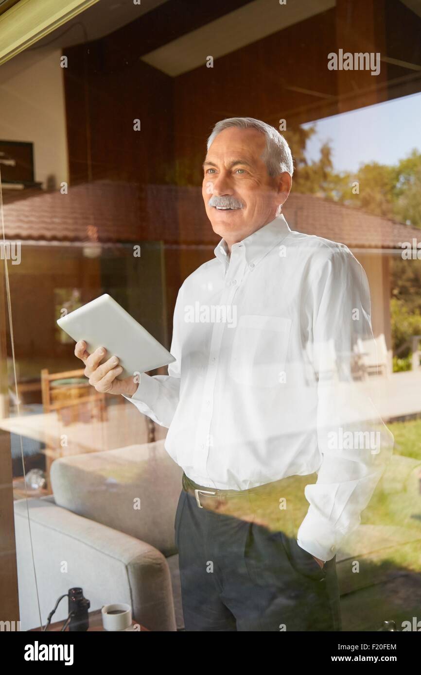 Senior man at home, holding digital tablet Stock Photo