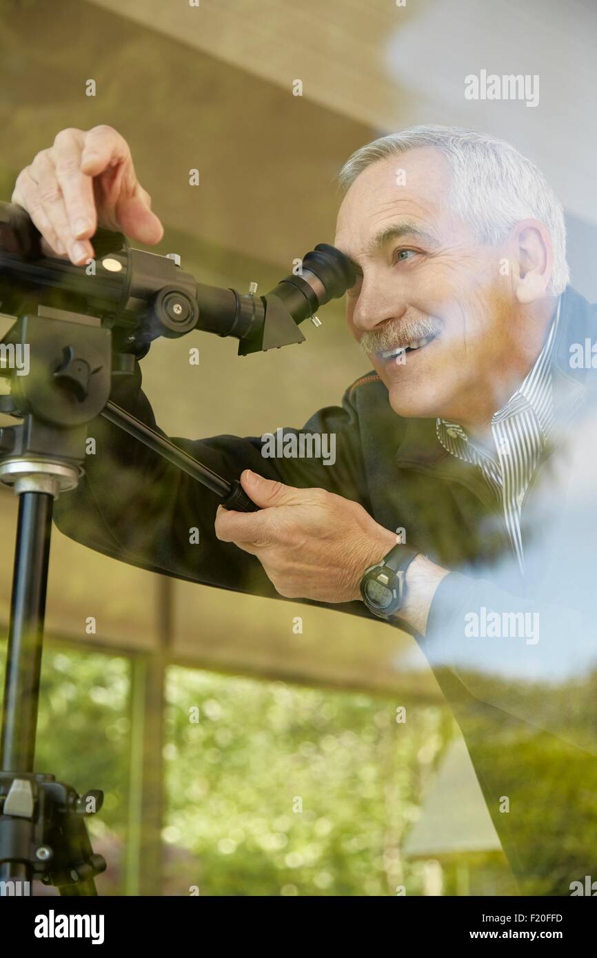 Senior man at home using telescope through window Stock Photo Alamy