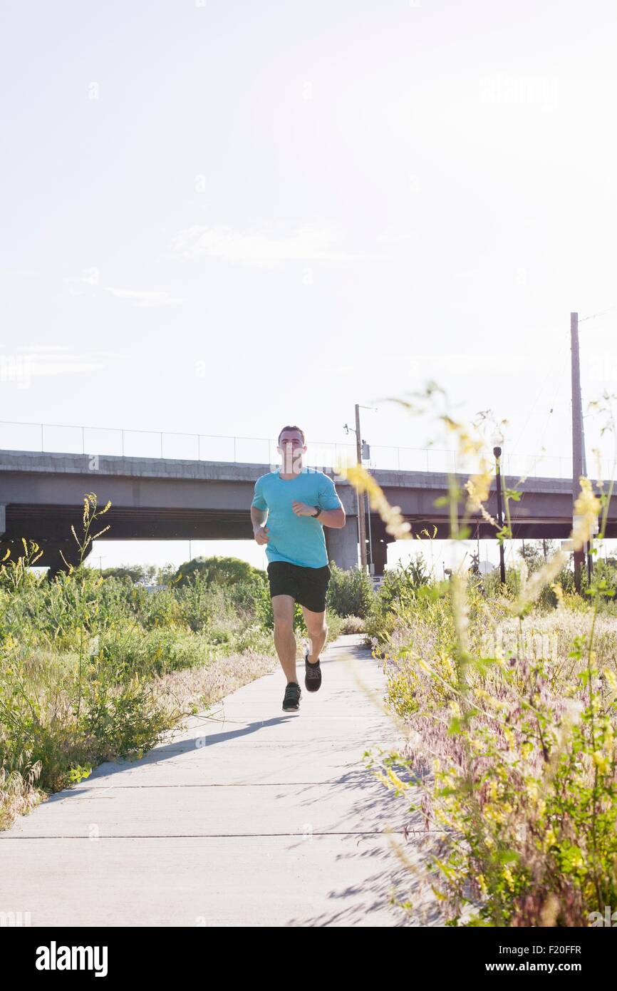 Young male runner running along path Stock Photo