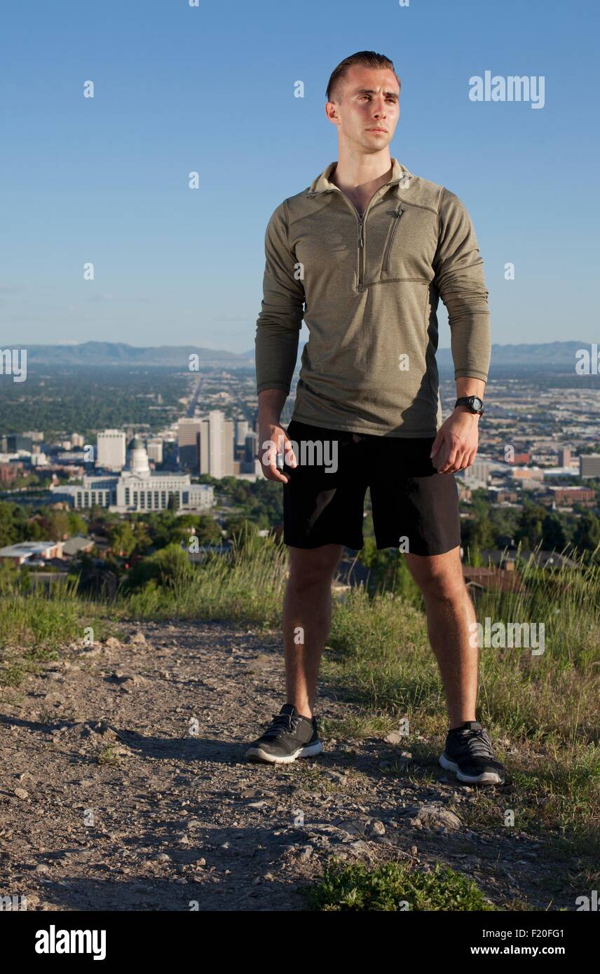 Portrait of young male runner on dirt track above city in valley Stock Photo