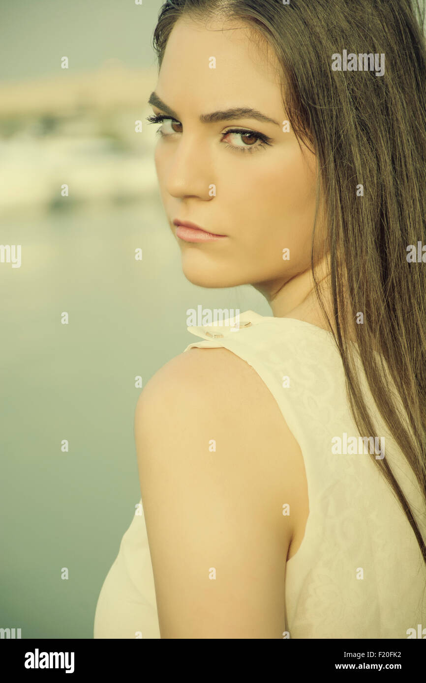 Serious young woman looking over shoulder outdoors Stock Photo