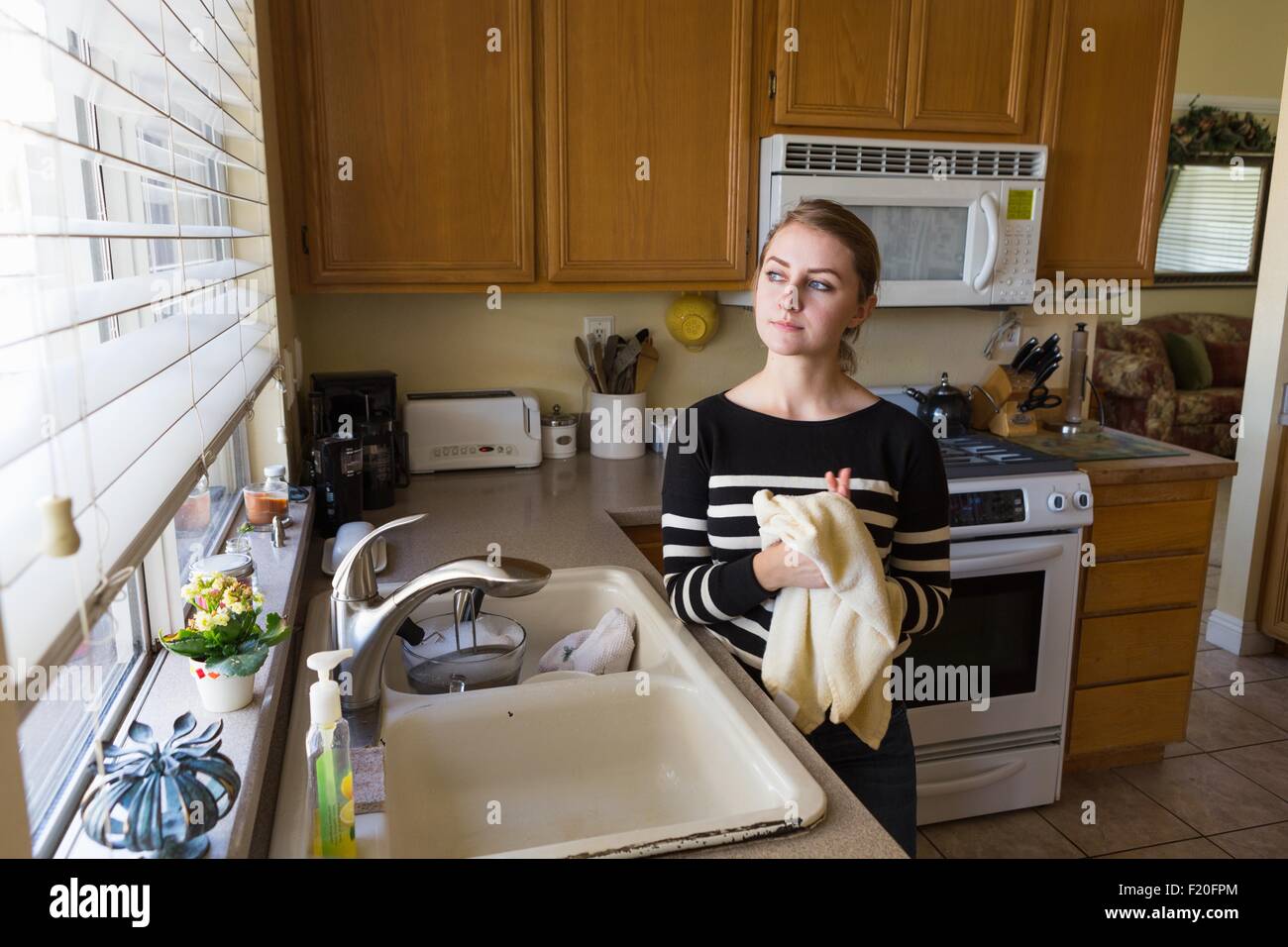 Woman daydreaming in kitchen Stock Photo