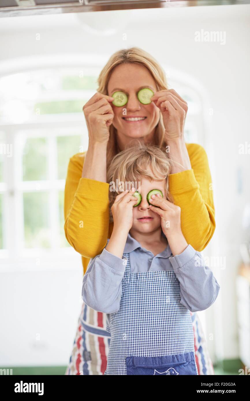Mother and son covering eyes with cucumber slices Stock Photo