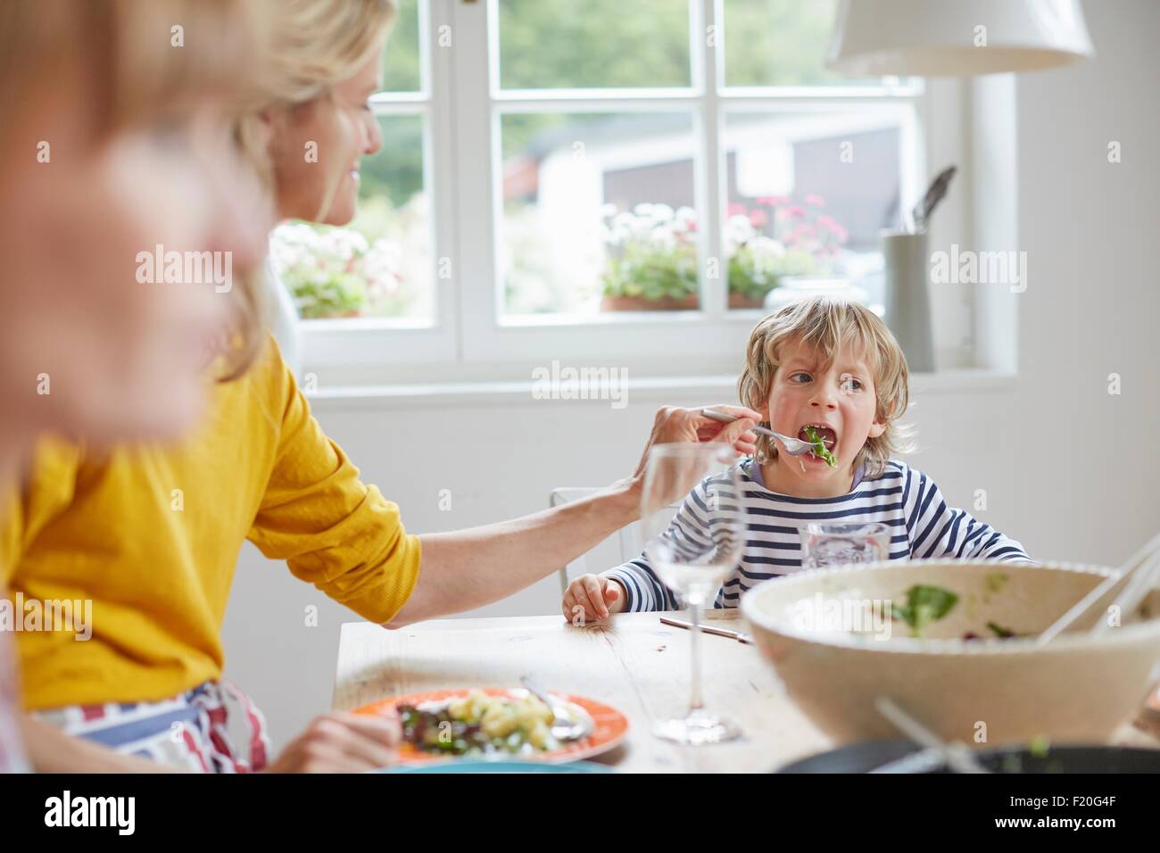 Mother feeding son at dining table Stock Photo