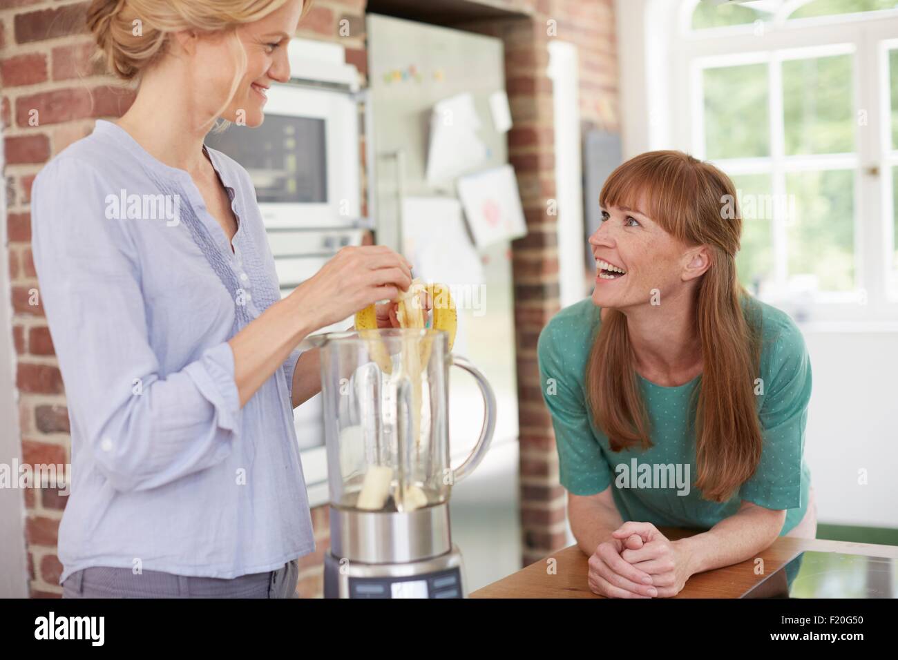 Women using blender and chatting in kitchen Stock Photo