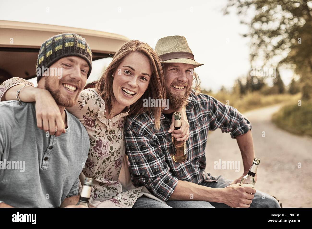 Three people holding beer bottles, looking at camera, smiling Stock Photo