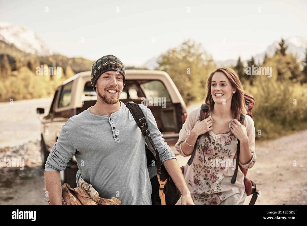 Young couple preparing to go hiking, carrying firewood, smiling Stock Photo