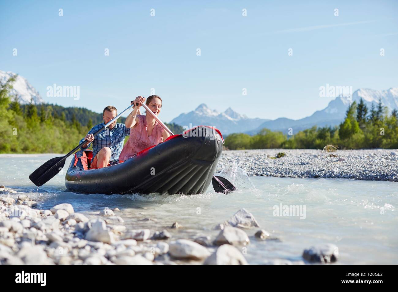 Couple using paddles to steer dinghy on water, Wallgau, Bavaria, germany Stock Photo