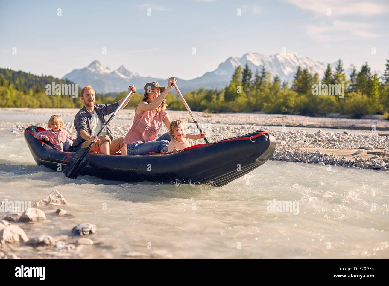 Family using paddles to steer dinghy on water, Wallgau, Bavaria, germany Stock Photo