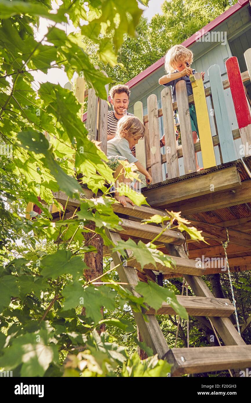 Father and two sons, painting tree house, low angle view Stock Photo