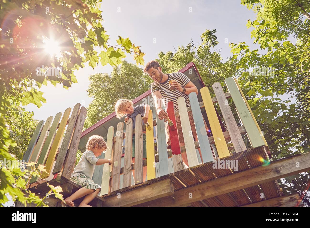 Father and two sons, painting tree house, low angle view Stock Photo