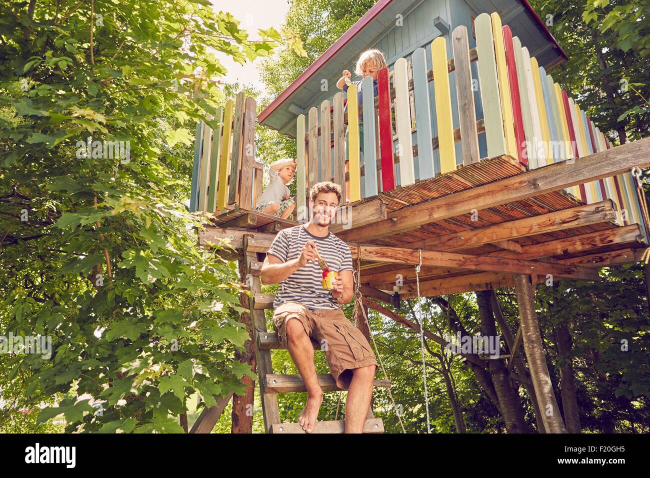Portrait of father and two sons painting tree house Stock Photo