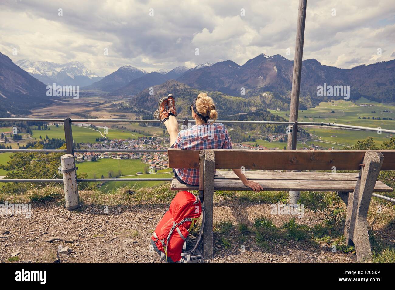 Mature woman sitting on bench, looking at mountain view, Garmisch-Partenkirchen, Bavaria, Germany Stock Photo