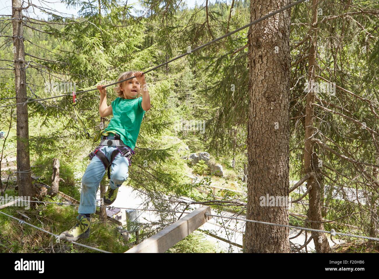 Boy moving along rope in forest, Ehrwald, Tyrol, Austria Stock Photo