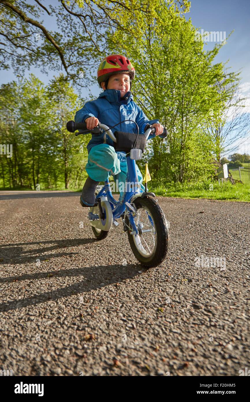 Boy wearing red cycle helmet cycling on rural road Stock Photo