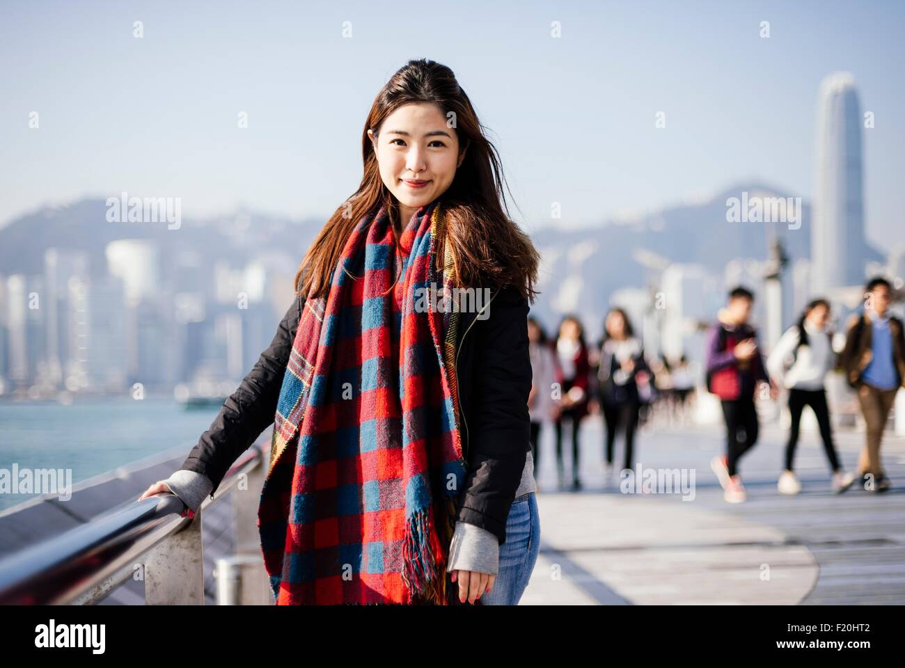 Portrait of young woman wearing checked scarf and leather jacket, looking at camera Stock Photo
