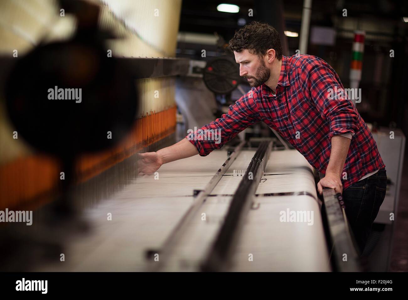 Young male weaver using old weaving machine in textile mill Stock Photo