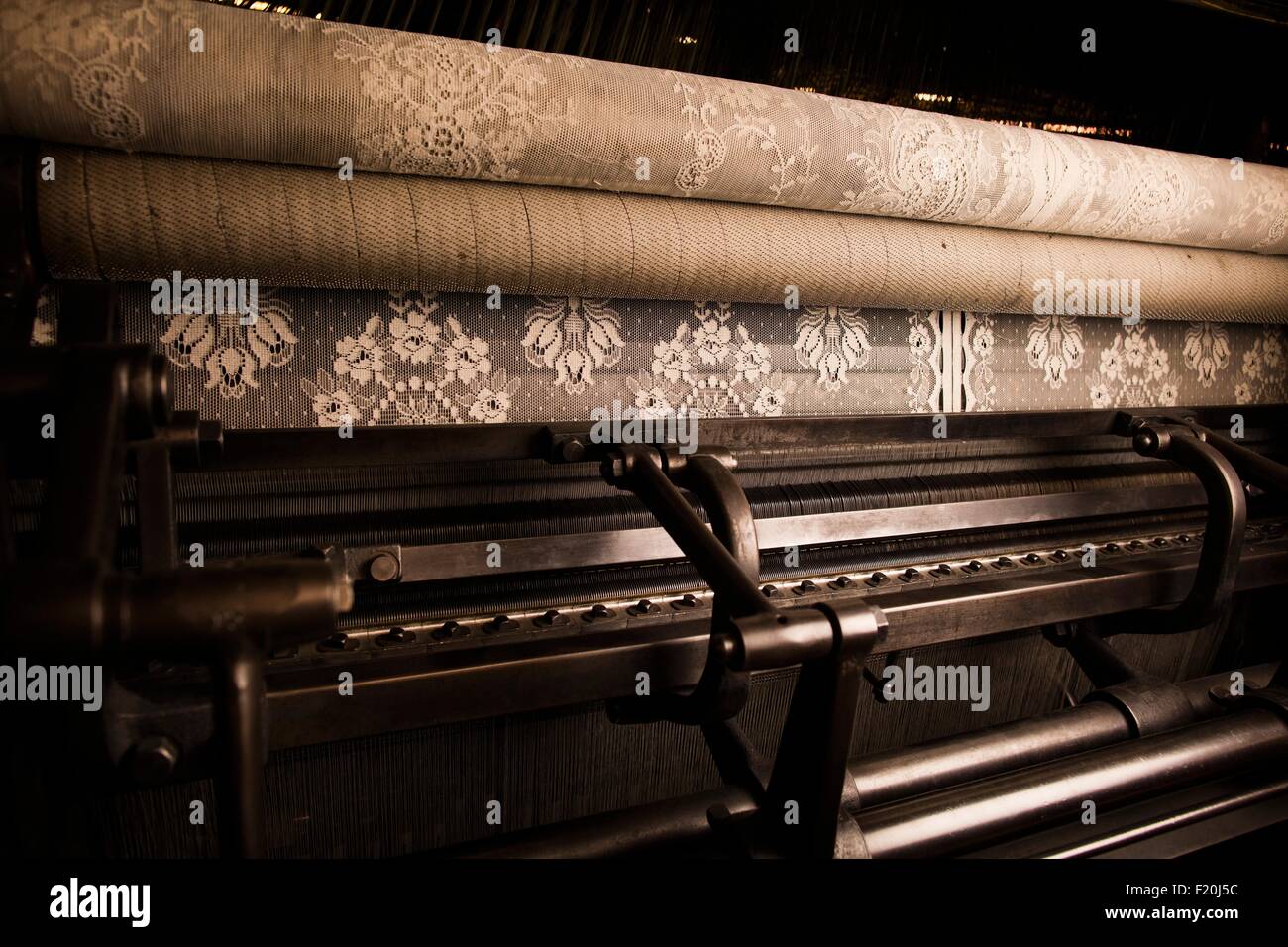 Intricate lace on old weaving machine in textile mill Stock Photo