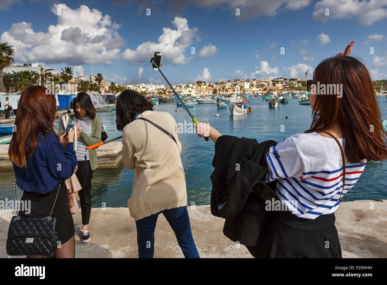 Malta, Marsaxlokk, Japanese tourists making selfies the edge of the water in a fishing village Stock Photo