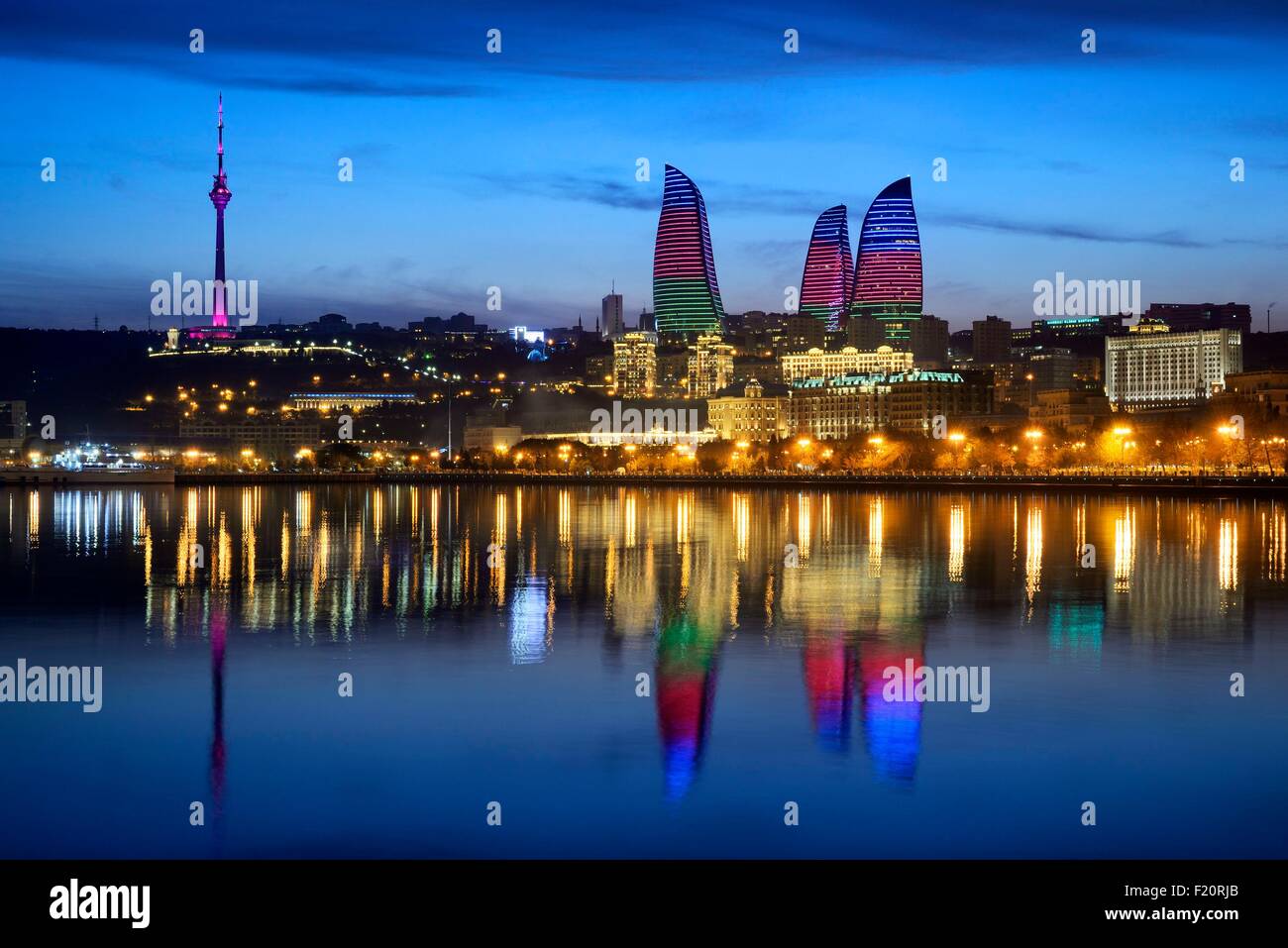 Azerbaijan, Baku, Baku Bulvar (Boulevard), city illuminated at dusk reflected in the Caspian sea, the Flame Towers with the colours of the national flag and the TV Tower Stock Photo
