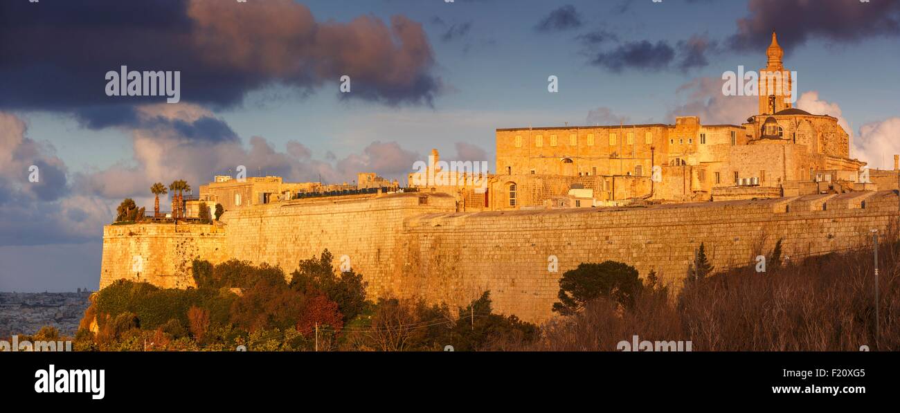Malta, Mdina, panoramic views of the walls of a fortified city and its religious monuments at sunset under a cloudy sky Stock Photo
