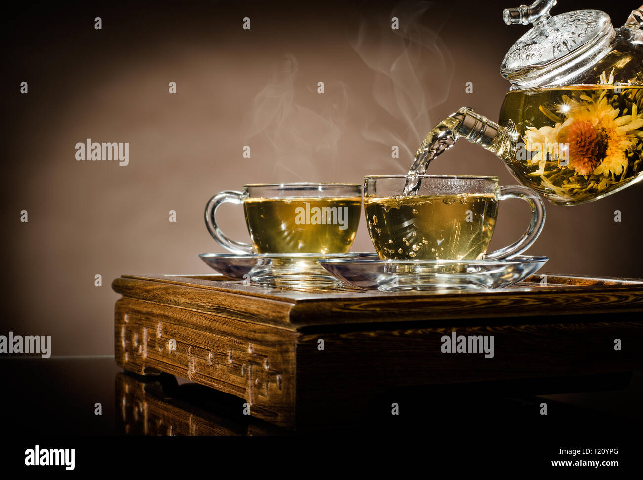 horizontal photo, of the glass teapot flow green tea in cup on brown background,  tea ceremony Stock Photo